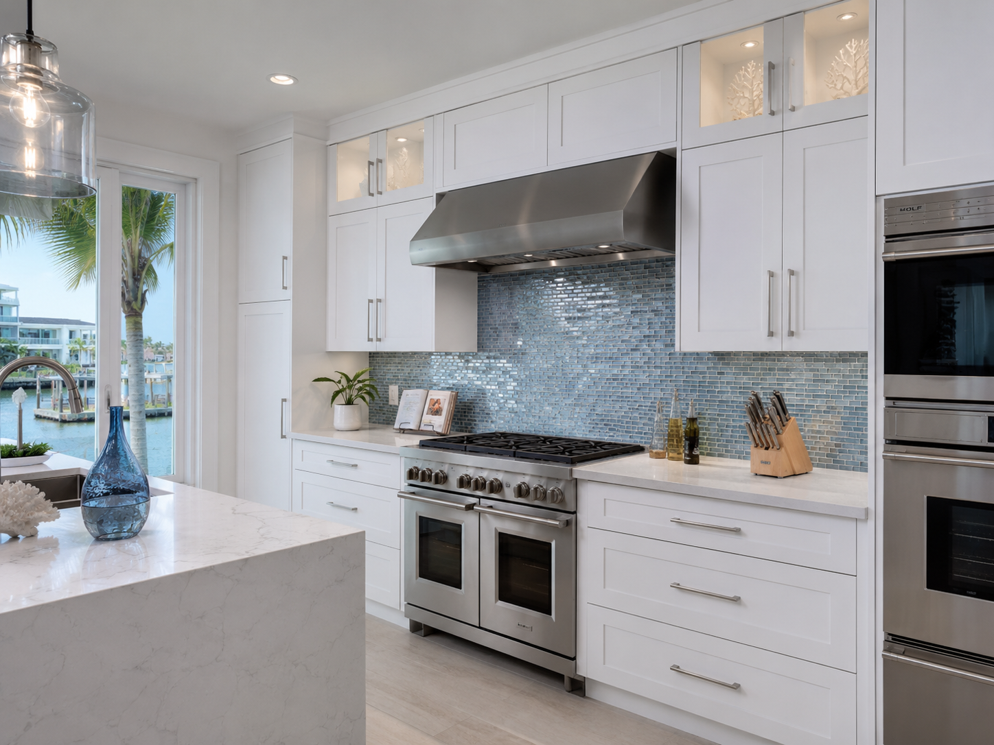 Glossy blue tiled kitchen backsplash with white cabinetry and stainless appliances