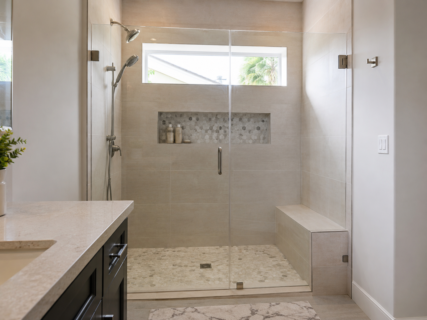 Wide glass shower with integrated bench, natural stone floor, and transom window