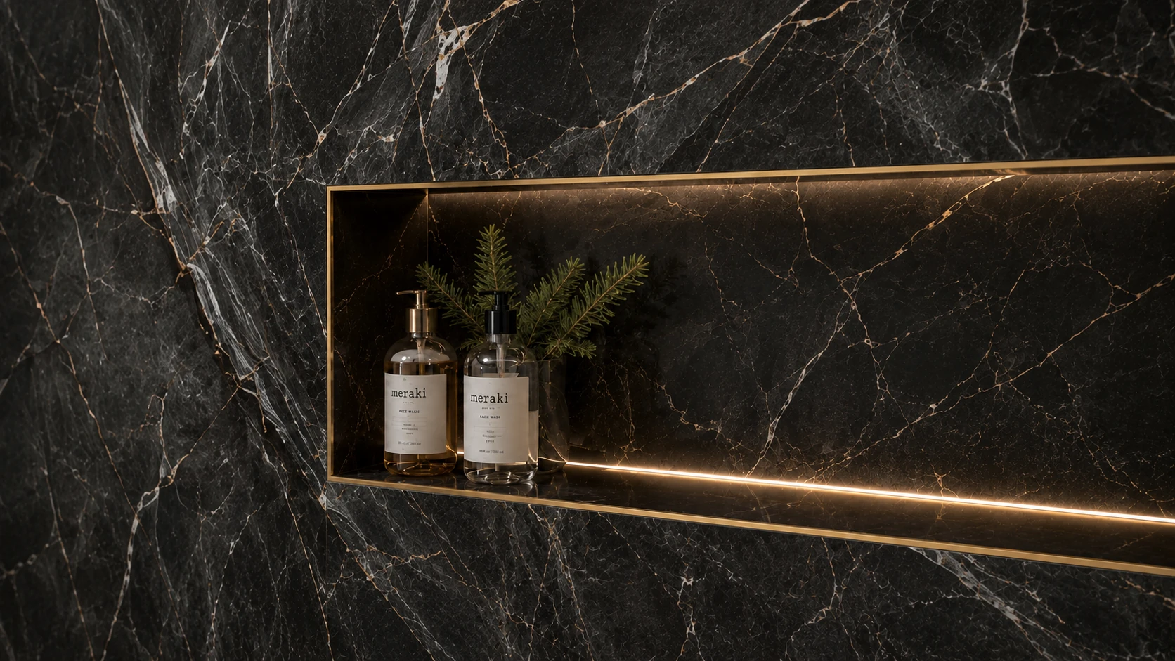 Custom recessed shower niche finished with dark marble-look tile, flush brass trim, and integrated lighting